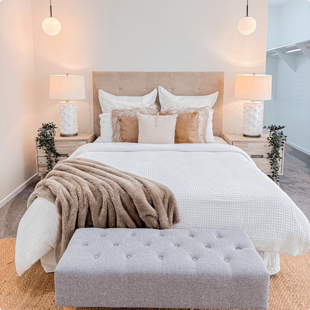 Large professionally styled bedroom with coordinated neutral furniture